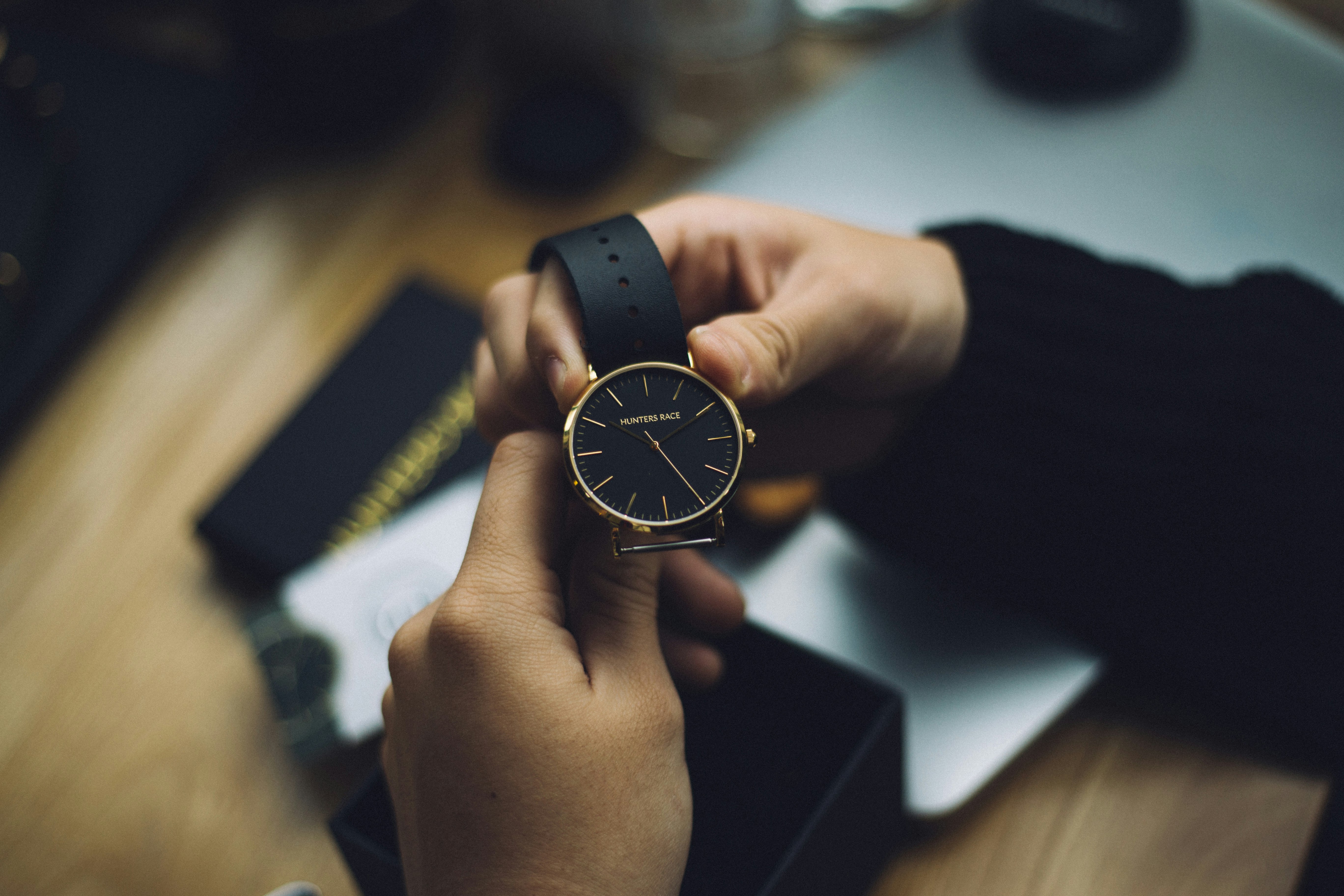 person holding gold-colored analog watch with black strap